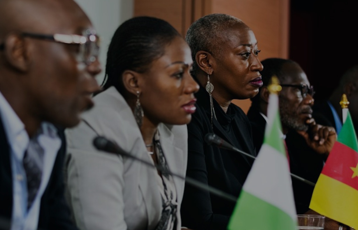 Delegates seated at a conference table with national flags